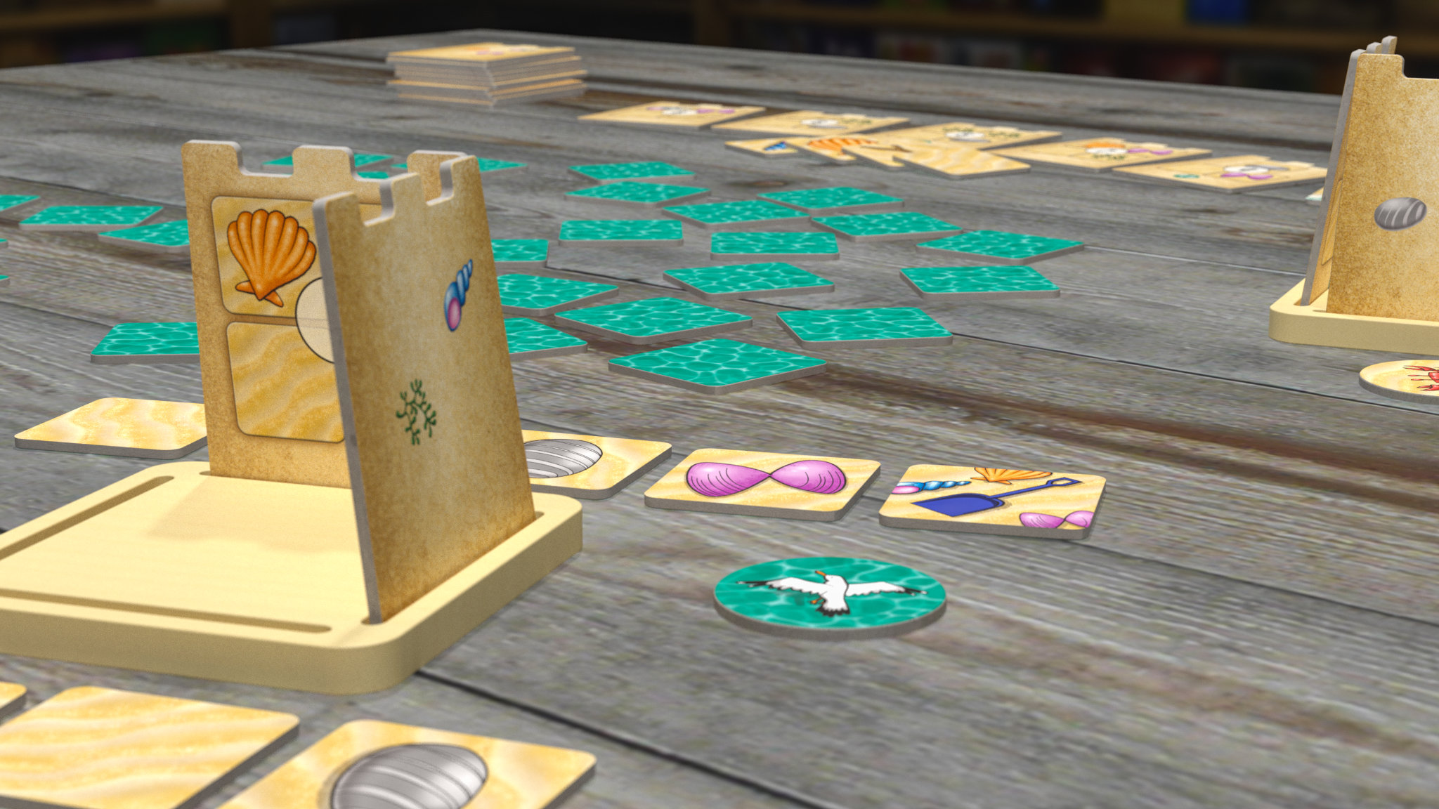 A wide shot of the game in play on a table. There is a partially built sand castle in the foreground, and another at the back right. Between them are decoration tiles and some helpful critters.